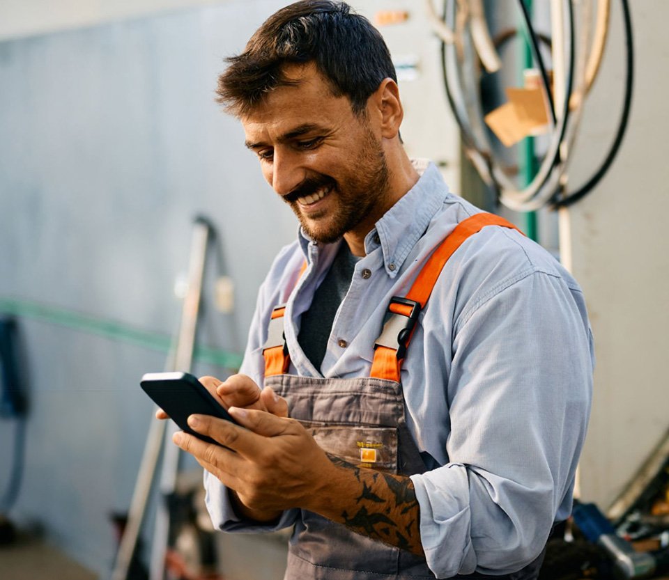 Contractor smiling while checking his phone after successful contractor marketing campaign